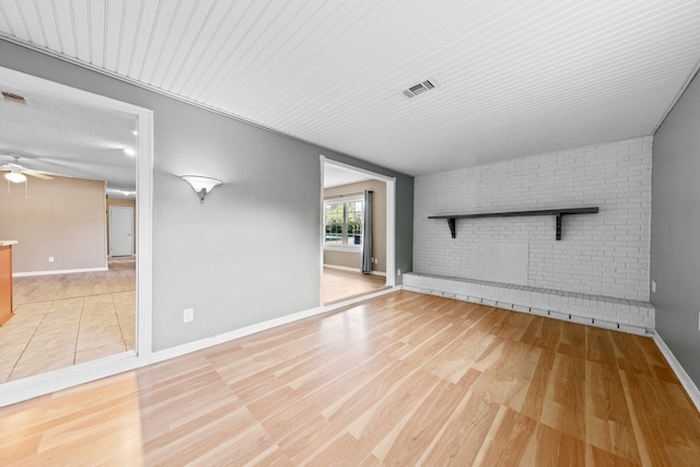 spare room with light hardwood / wood-style flooring, ceiling fan, and brick wall