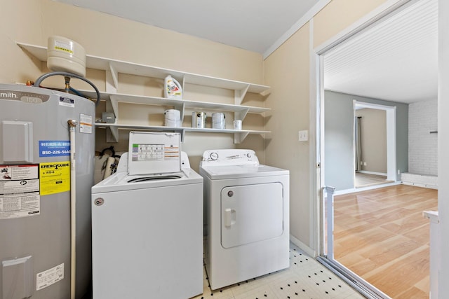 clothes washing area featuring light hardwood / wood-style flooring, water heater, and washing machine and dryer