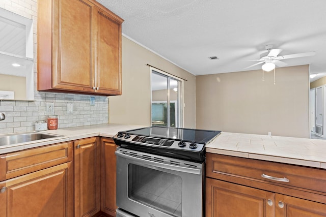 kitchen featuring decorative backsplash, kitchen peninsula, stainless steel range with electric stovetop, ceiling fan, and sink