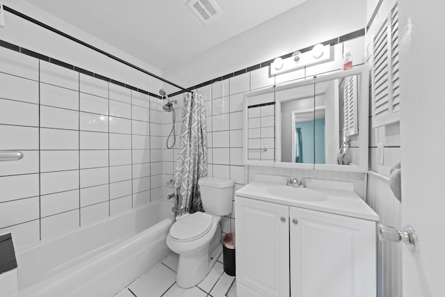 full bathroom with tile walls, shower / bathtub combination with curtain, tile patterned floors, vanity, and toilet