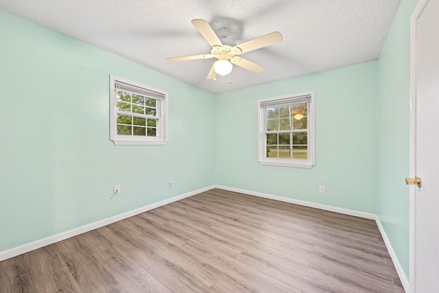 spare room with light wood-type flooring, ceiling fan, and plenty of natural light