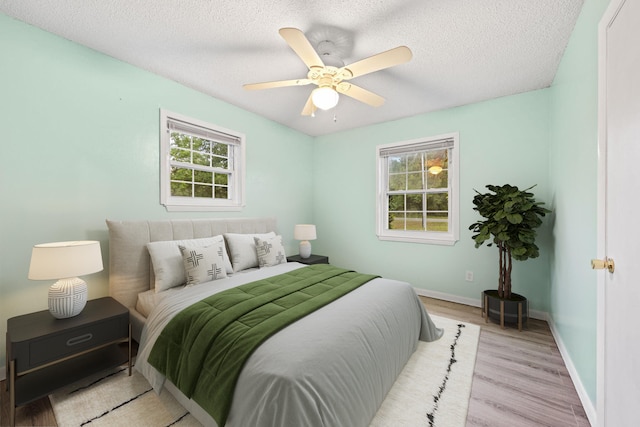 bedroom featuring light wood-type flooring, ceiling fan, and a textured ceiling