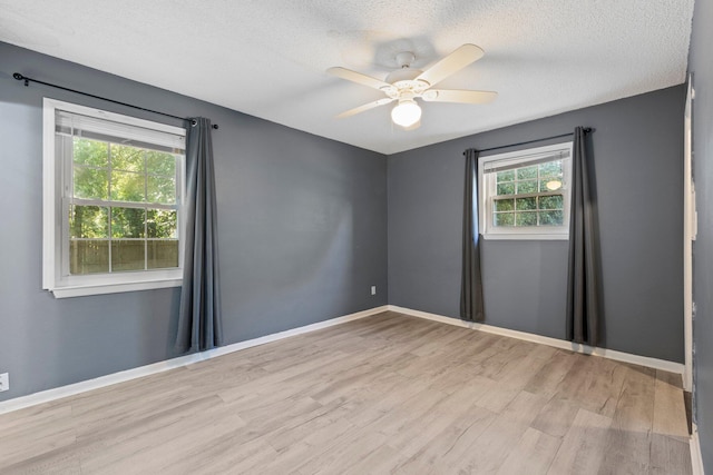 empty room with a textured ceiling, ceiling fan, and light hardwood / wood-style flooring