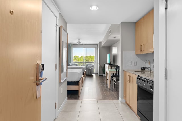 kitchen featuring ceiling fan, light brown cabinets, hanging light fixtures, sink, and black dishwasher