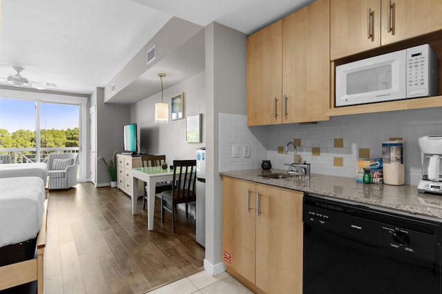 kitchen with dark stone counters, black dishwasher, light hardwood / wood-style flooring, decorative light fixtures, and sink