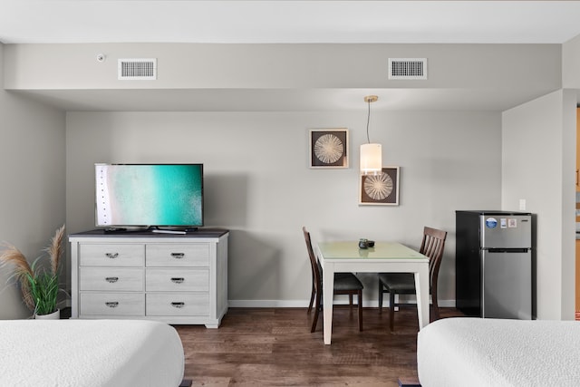 bedroom featuring stainless steel fridge and dark hardwood / wood-style floors