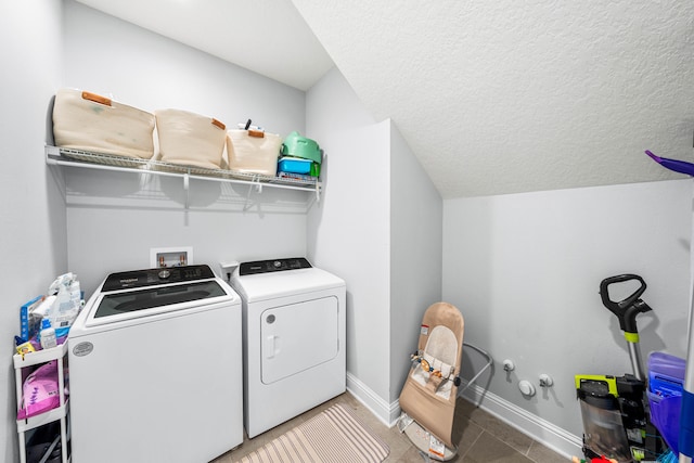 laundry area with washing machine and clothes dryer and a textured ceiling