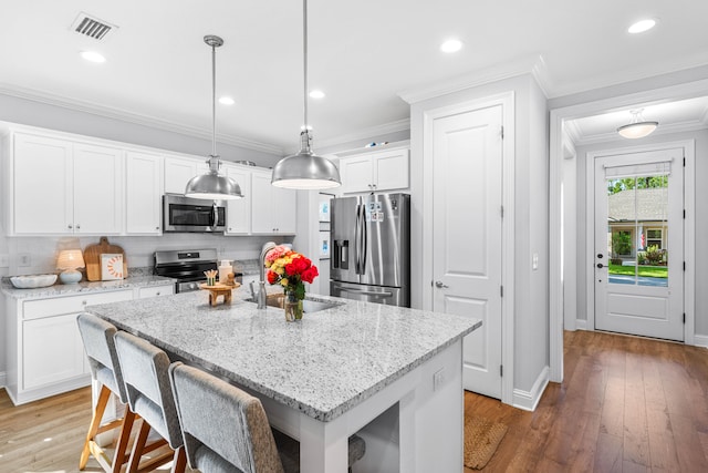 kitchen featuring white cabinetry, stainless steel appliances, a center island with sink, decorative light fixtures, and dark hardwood / wood-style flooring