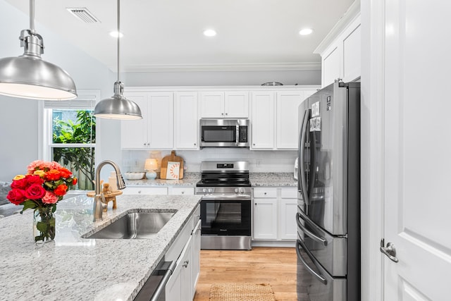 kitchen with white cabinets, light stone countertops, stainless steel appliances, decorative light fixtures, and sink