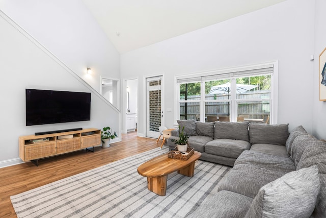 living room with light hardwood / wood-style floors and high vaulted ceiling