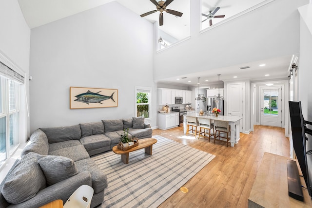 living room featuring light wood-type flooring, ceiling fan, and high vaulted ceiling