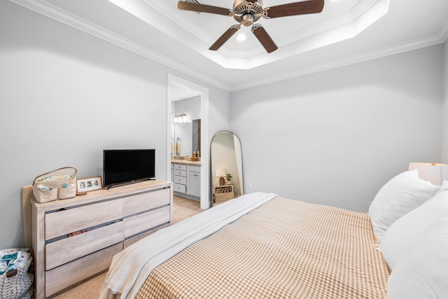 bedroom featuring crown molding, ceiling fan, ensuite bathroom, and a raised ceiling