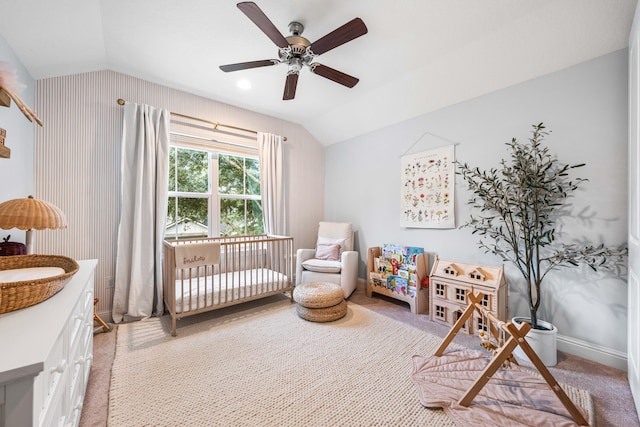 bedroom featuring a crib, lofted ceiling, light carpet, and ceiling fan