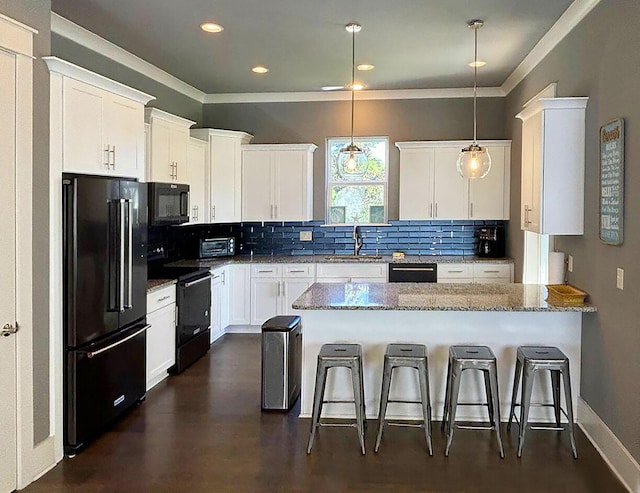 kitchen featuring a kitchen breakfast bar, black appliances, light stone counters, and white cabinets