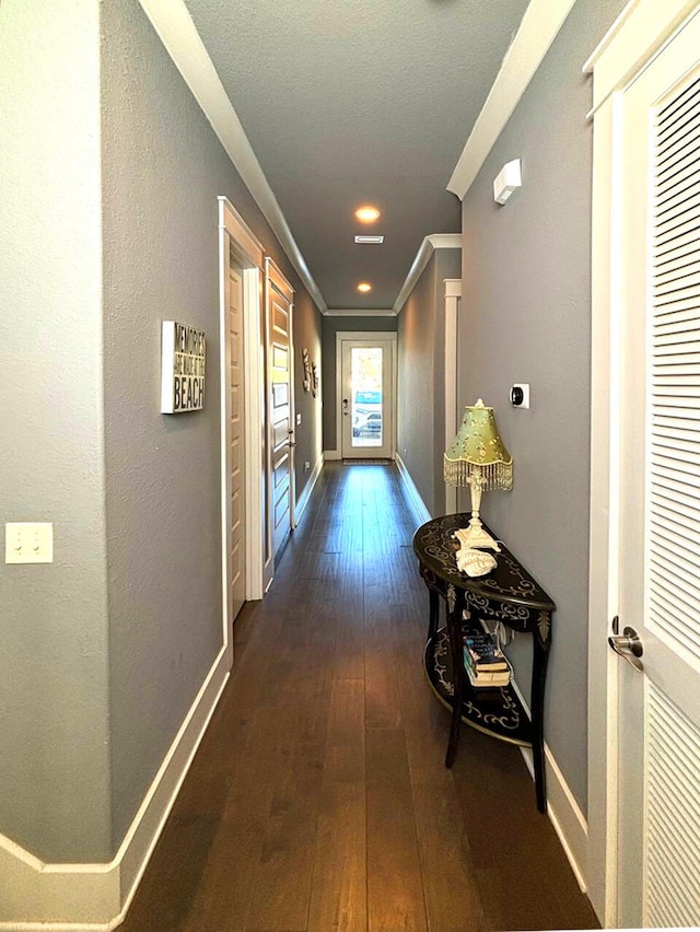 hall with ornamental molding and dark wood-type flooring