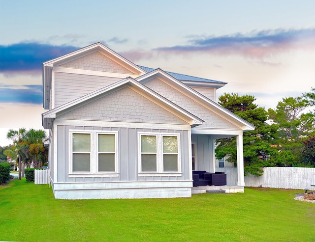 back house at dusk featuring a lawn