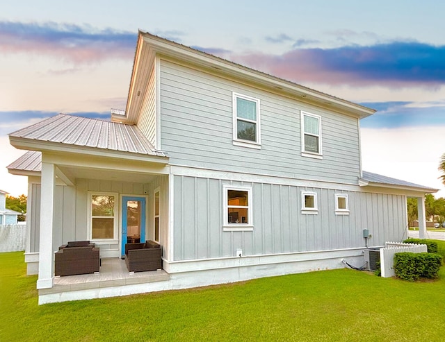 back house at dusk with outdoor lounge area and a yard