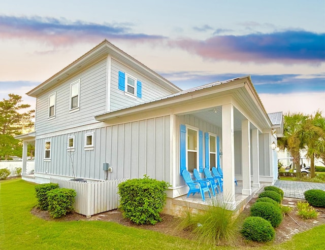 property exterior at dusk with a lawn and a porch