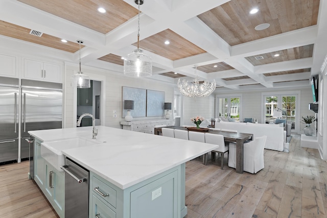 kitchen with stainless steel built in fridge, pendant lighting, beamed ceiling, a center island with sink, and light hardwood / wood-style flooring