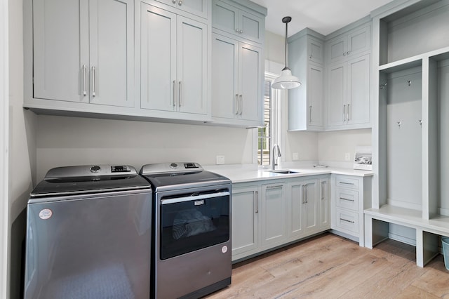 washroom featuring light wood-type flooring, separate washer and dryer, sink, and cabinets