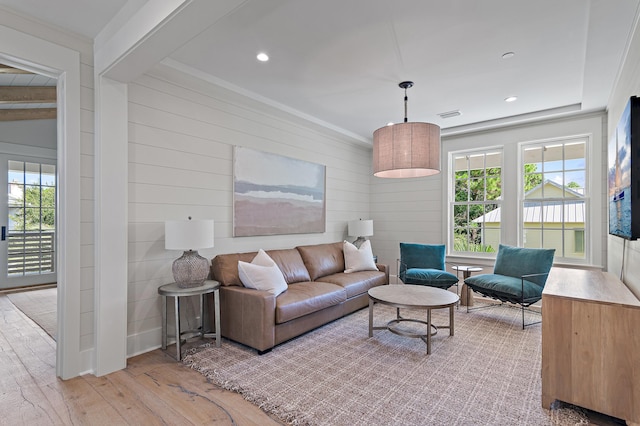 living room featuring ornamental molding, beam ceiling, light hardwood / wood-style floors, and wood walls