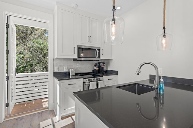 kitchen with hanging light fixtures, sink, stainless steel appliances, and white cabinets