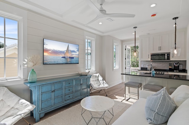 living room with light hardwood / wood-style flooring, ceiling fan, and sink