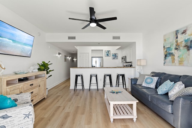 living room featuring ceiling fan and light hardwood / wood-style floors