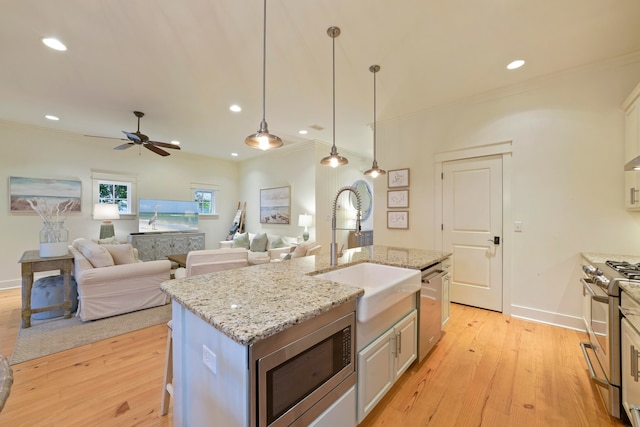 kitchen with sink, a center island with sink, decorative light fixtures, appliances with stainless steel finishes, and light hardwood / wood-style floors