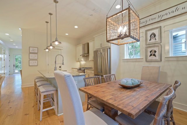 dining area with ornamental molding, sink, and light hardwood / wood-style flooring