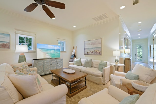 carpeted living room featuring ornamental molding, ceiling fan, and a wealth of natural light