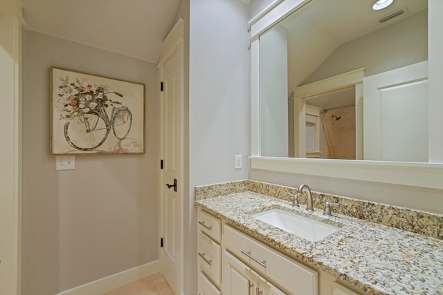 bathroom with lofted ceiling, vanity, and tile patterned floors