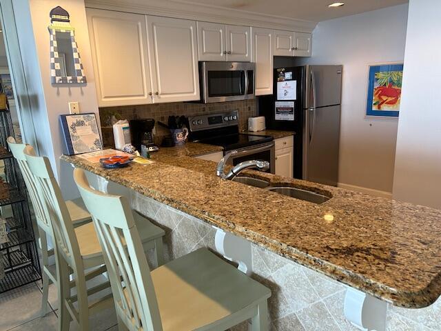 1751 Scenic Highway 98 Unit 614, Destin, FL 32541 - kitchen featuring stainless steel appliances, a sink, backsplash, and white cabinetry