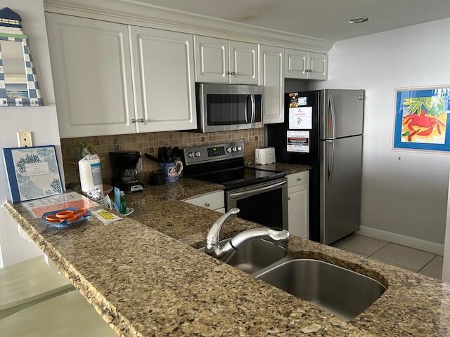 1751 Scenic Highway 98 Unit 614, Destin, FL 32541 - kitchen featuring stainless steel appliances, a sink, white cabinetry, tasteful backsplash, and light tile patterned floors