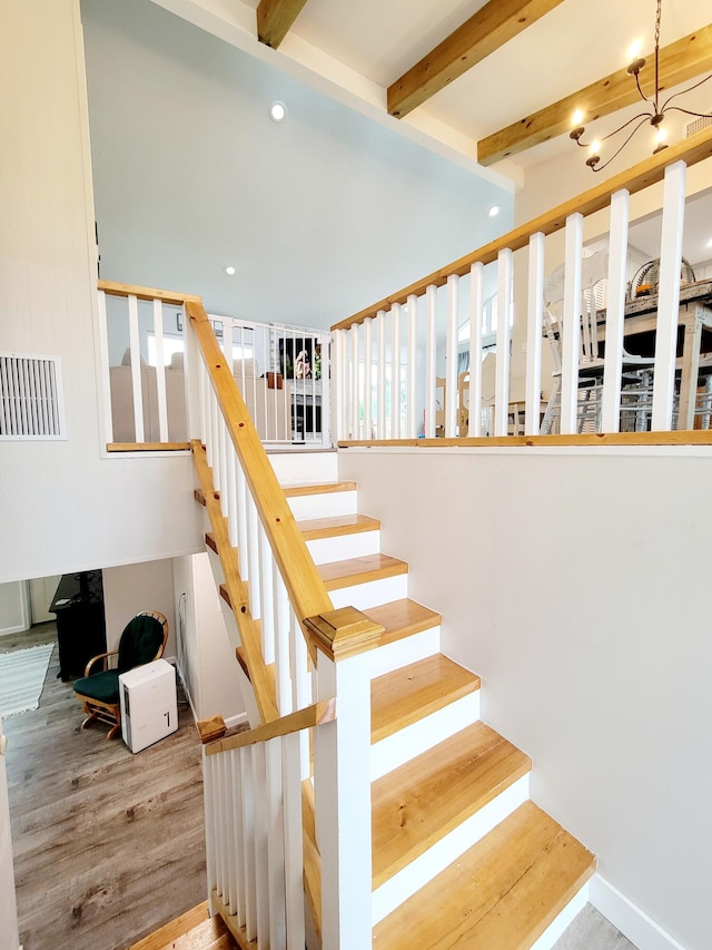 stairs with beam ceiling and hardwood / wood-style flooring