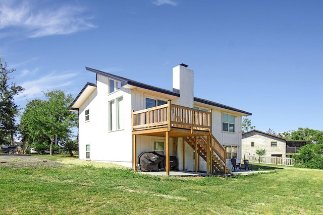 rear view of house with a patio, a wooden deck, and a lawn