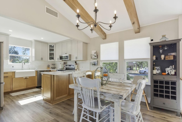 dining area featuring hardwood / wood-style flooring, sink, a wealth of natural light, and lofted ceiling with beams