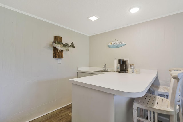 interior space with sink, kitchen peninsula, crown molding, a breakfast bar area, and dark hardwood / wood-style floors