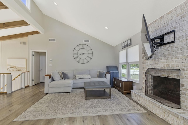 living room featuring high vaulted ceiling, beamed ceiling, a brick fireplace, and hardwood / wood-style floors