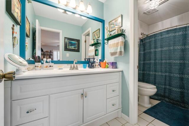 bathroom with tile patterned flooring, a shower with curtain, vanity, and toilet