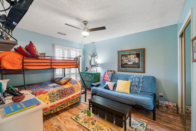 bedroom featuring a closet, ceiling fan, hardwood / wood-style flooring, and a textured ceiling