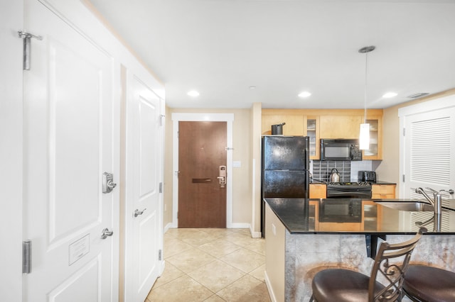 kitchen featuring pendant lighting, sink, backsplash, black appliances, and a kitchen breakfast bar