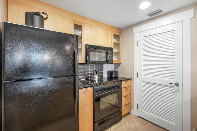 kitchen with light tile patterned flooring, light brown cabinetry, black appliances, and decorative backsplash