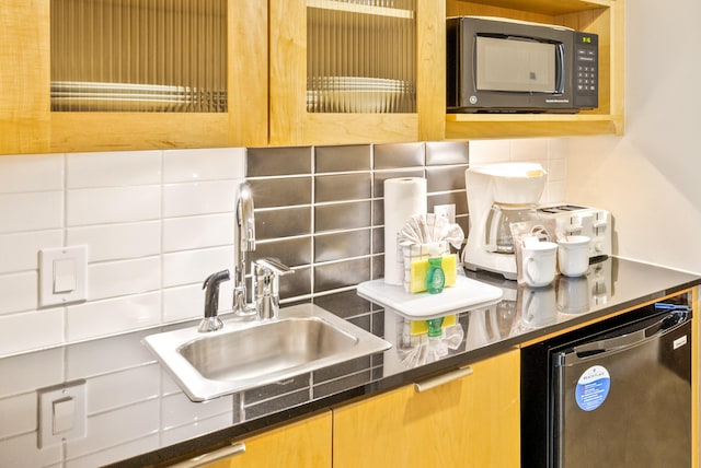 kitchen featuring decorative backsplash, dark stone counters, sink, and stainless steel dishwasher