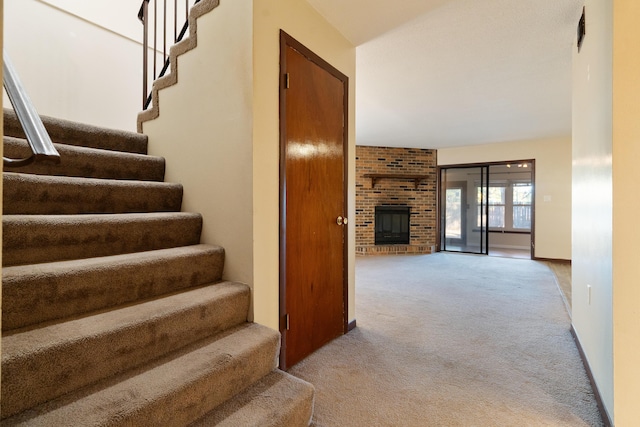 stairway featuring carpet floors and a brick fireplace