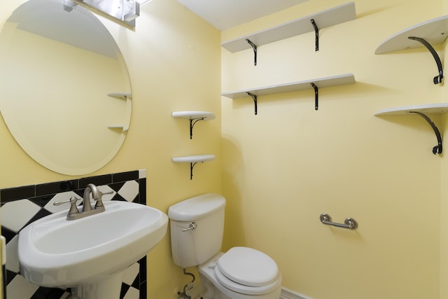 bathroom featuring backsplash, toilet, and sink