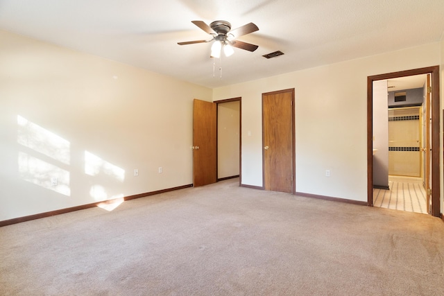 unfurnished bedroom with ceiling fan, light carpet, and ensuite bath