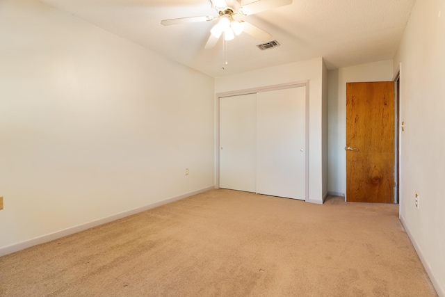 unfurnished bedroom featuring light carpet, a closet, and ceiling fan