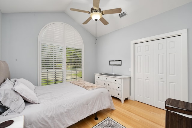 bedroom with ceiling fan, vaulted ceiling, a closet, and light hardwood / wood-style floors