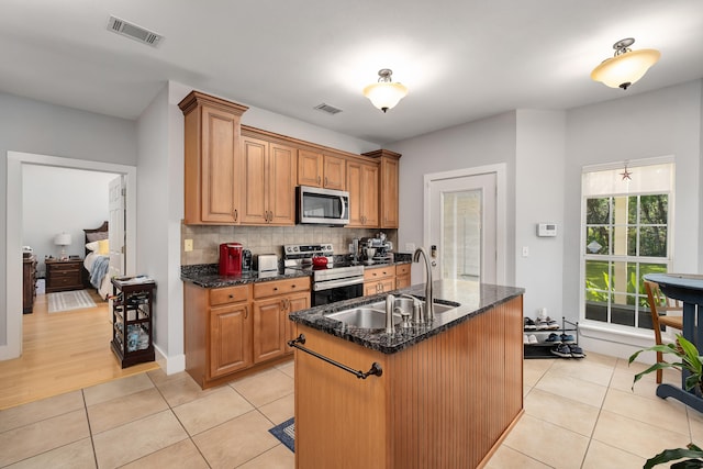 kitchen featuring light tile patterned floors, a center island with sink, appliances with stainless steel finishes, and sink